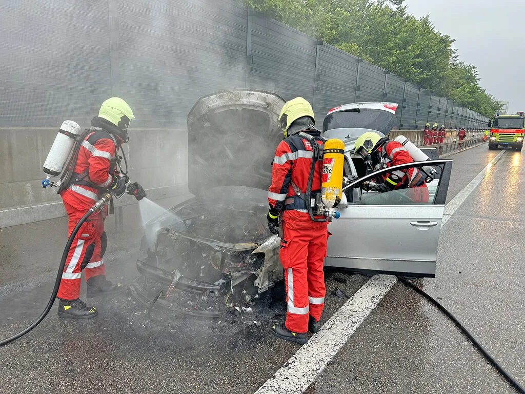 Da ist nichts mehr zu machen: Der Brand verursachte einen Totalschaden. Ein ausgebranntes Auto und löschende Feuerwehrleute
